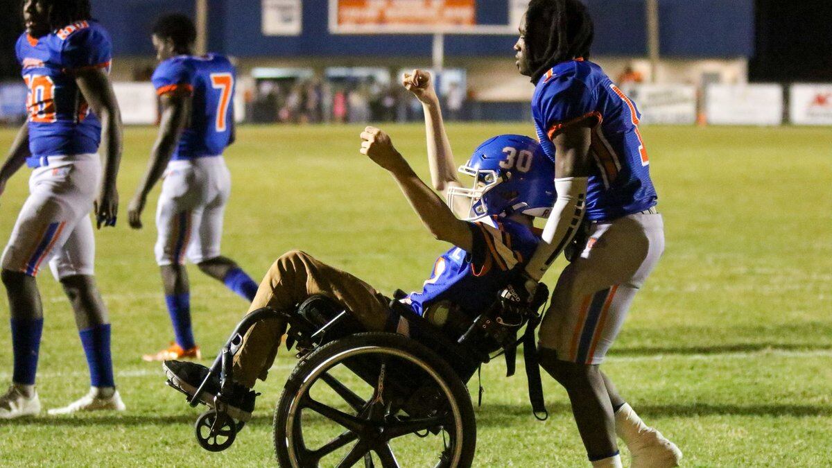 The Taylor County football team helped wheelchair-bound fan Cycless Gorlewski across the goal...