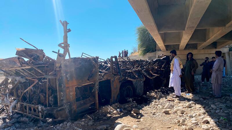 People look at the burnt wreckage of a bus accident in Bela, an area of Lasbela district of...