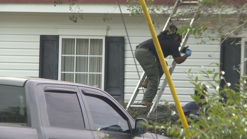 An investigator takes photos through a second story window of home where man was murdered on...