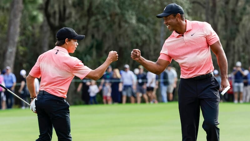 Tiger Woods, right, fist bumps his son Charlie Woods, left, after finishing the 9th hole...