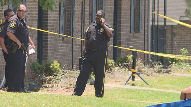 Ozark police stand outside an apartment where the body of a man was found shot to death. ...