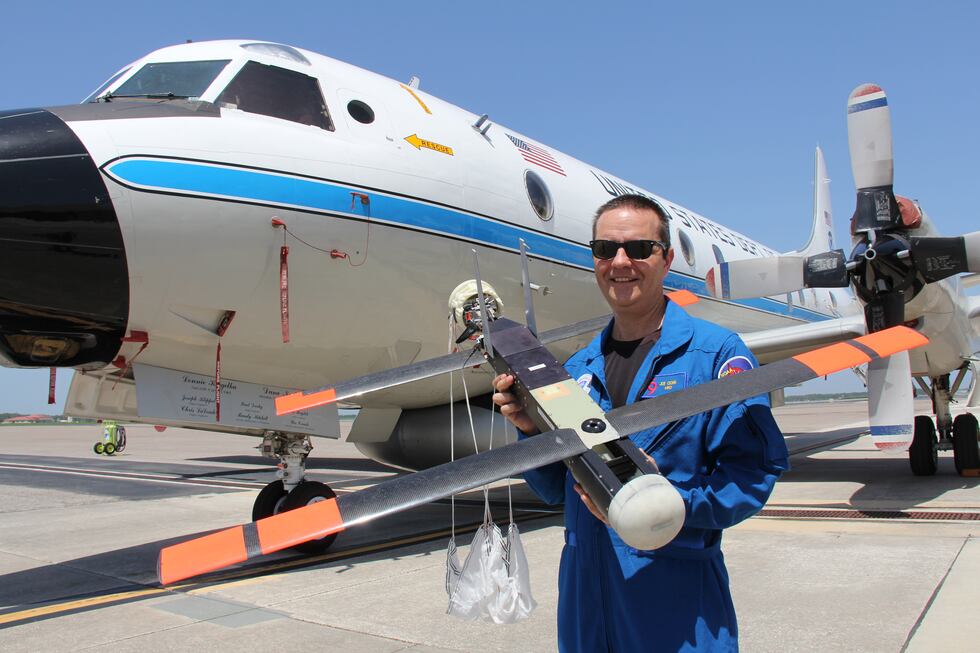 Dr. Cione holds a earlier model of a UAS in front of t P-3 Orion