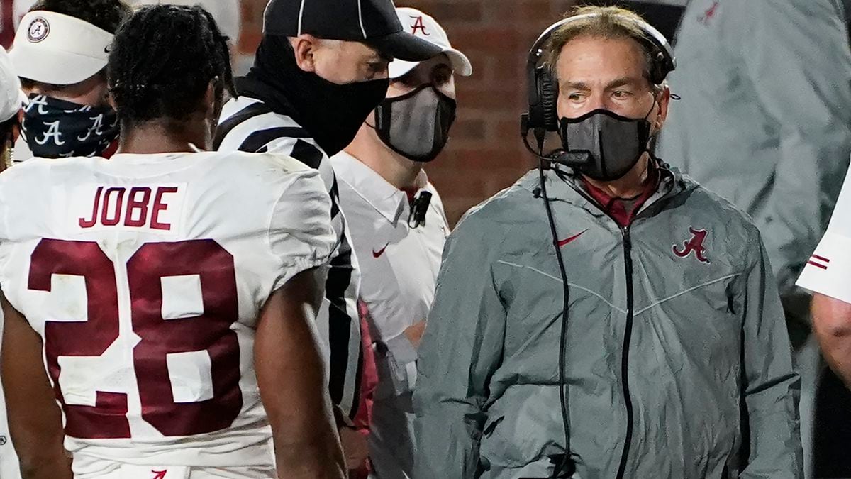 A masked Alabama coach Nick Saban speaks with defensive back Josh Jobe (28) during the second...